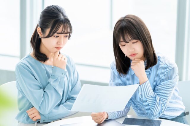 企業ブランディングアイデアの一覧を見て、考えている女性たち